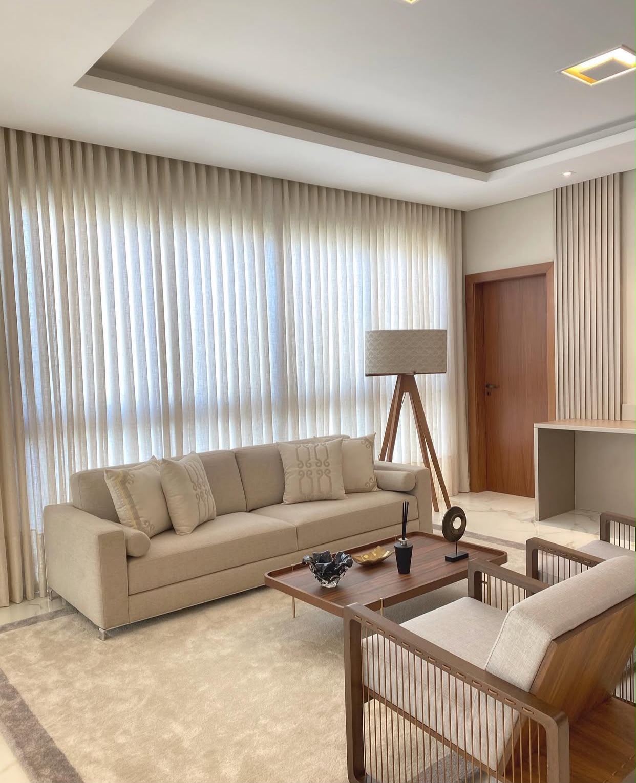 Sala com cortinas sob medida em tecido claro e caimento longo